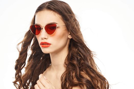 Portrait of brunette woman in sunglasses naked shoulders light background. High quality photo