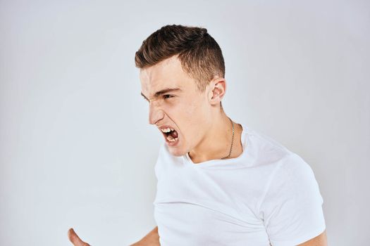 Emotional man gestures with his hands displeasure white t-shirt light background. High quality photo