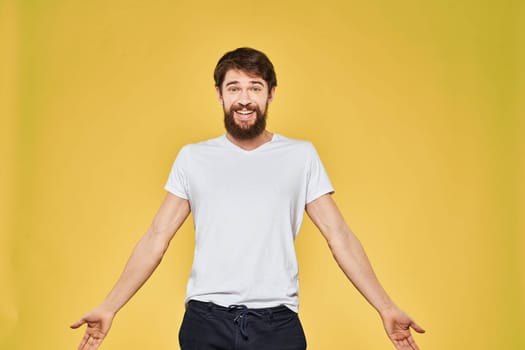 Man gesturing with hands emotions lifestyle white t-shirt yellow isolated background. High quality photo