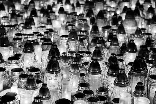 Candles burning on a grave in the cemetery of All Saints' Day in Poland, monochrome