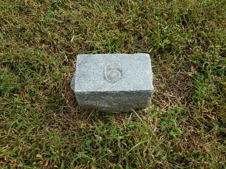 grey stone with number six in green grass