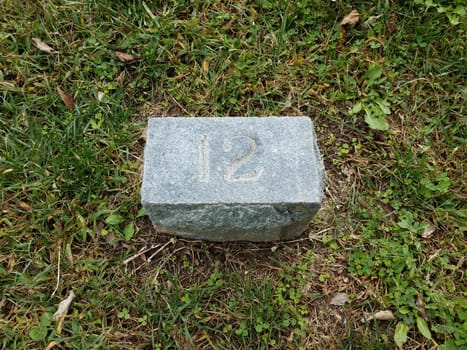 grey stone with number twelve in green grass