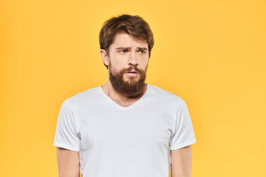 Bearded man emotions gestures with hands facial expression white t-shirt yellow background. High quality photo