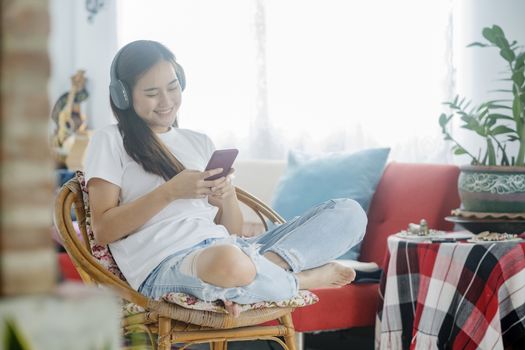 Quarantine Leisure. Young woman listening to music while sitting on sofa in room.