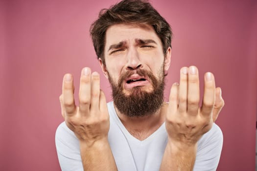 bearded man in white t-shirt emotions displeased facial expression studio pink background. High quality photo