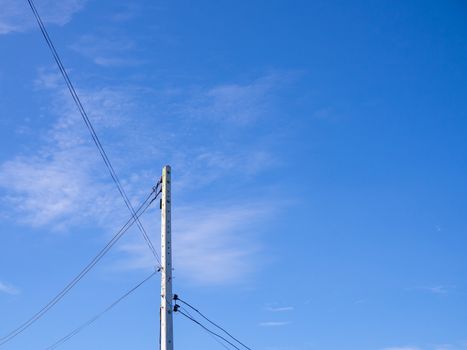 Electric poles and wires in a bright blue sky background.