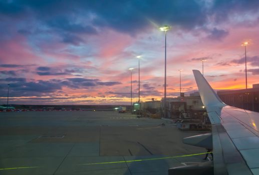 Peaceful twilight evening scene in the airport with a plane wing ready to depart