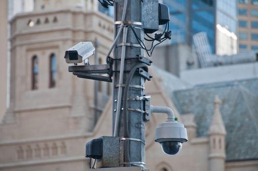 Surveillance CCTV street outdoor camera watching pedestrian near European church in city center to prevent terrorism. The photo is taken in the afternoon.