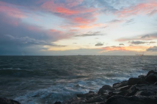 Dramatic splashing ocean wave in the evening with twilight sky in Winter at breakwater at St Kilda pier in Melbourne Australia