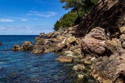 View on the coast at bay Cala Tuent on balearic island Mallorca, Spain on a sunny day with clear blue water and rocky coastline