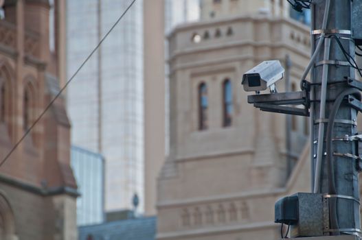 Surveillance CCTV street outdoor camera watching pedestrian near European church in city center to prevent terrorism. The photo is taken in the afternoon.