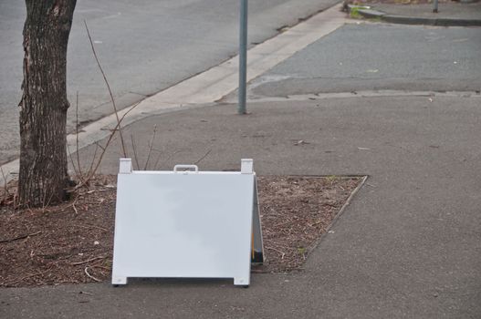 White plastic signboard placed on a street by a real estate company