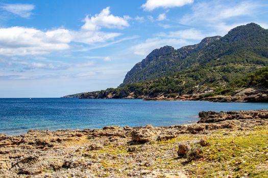 Bay on the peninsula La Victoria, Mallorca with ridge in the background, blue water and rocks in the sea