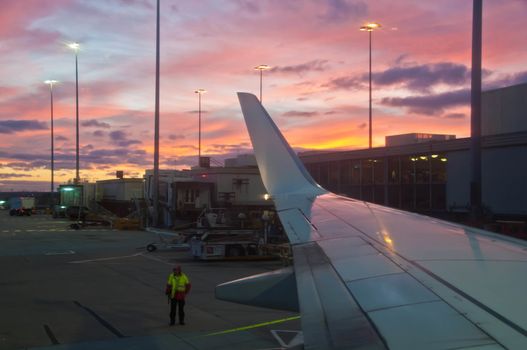 MELBOURNE, AUSTRALIA - JULY 30, 2018: Ground staff is standing by near a plane ready to take off at Melbourne Airport in the evening