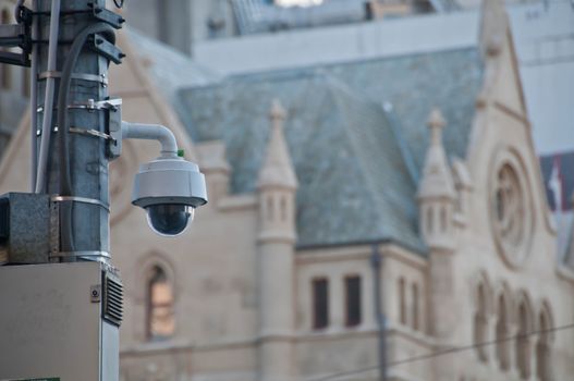 Surveillance CCTV street outdoor camera watching pedestrian near European church in city center to prevent terrorism. The photo is taken in the afternoon.