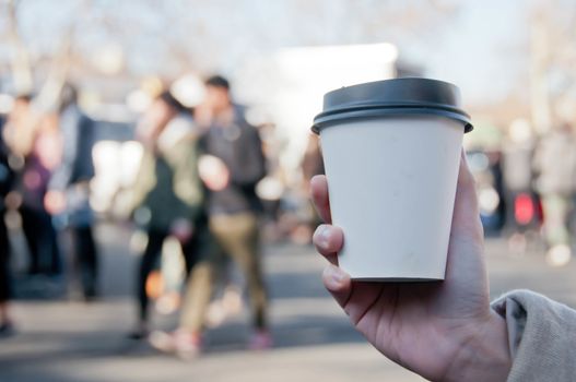 Take away white paper hot coffee cup with right hand holding in Sunday flea market