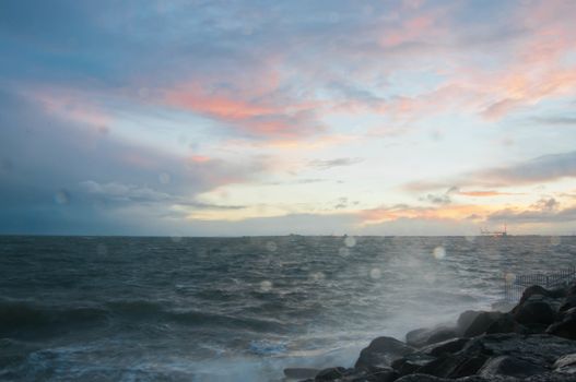 Dramatic splashing ocean wave in the evening with twilight sky in Winter at breakwater at St Kilda pier in Melbourne Australia