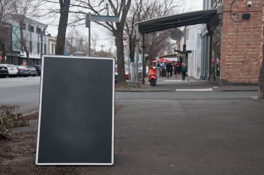 Black wooden signboard placed on a street by a real estate company