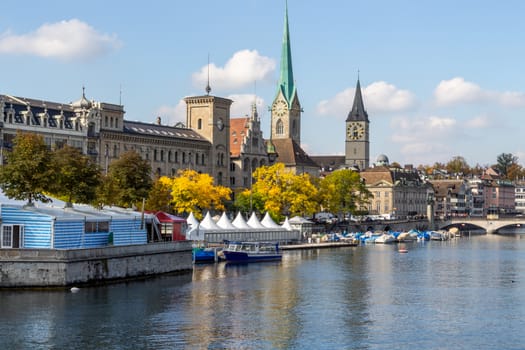 view at the waterfront of Limmat river in Zurich, Switzerland with ships, churchs and other buildings