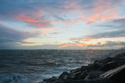 Dramatic splashing ocean wave in the evening with twilight sky in Winter at breakwater at St Kilda pier in Melbourne Australia