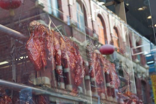 Roasted duck and BBQ pork hanged near Chinese restaurant window in Melbourne Australia