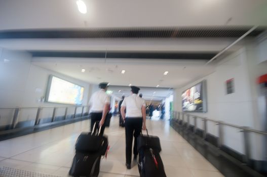 Blurry scene of rushing to follow 2 flight captains to the boarding gate in the airport