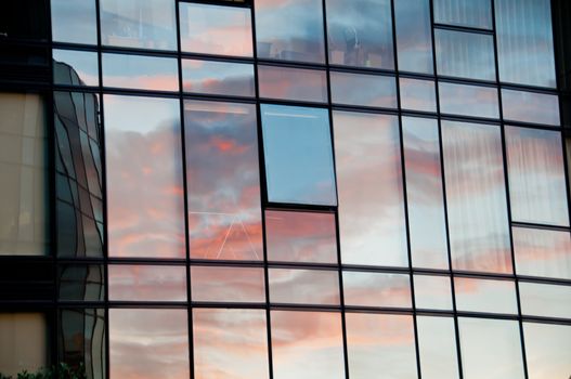 Reflection of pastel Sun set on window glass of modern corporate office building