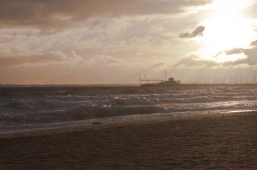 MELBOURNE, AUSTRALIA - JULY 29, 2018: Dramatic golden light ray from the sky in the afternoon with St Kilda pier and windy ocean in Melbourne bay and high tide wave. Nobody is in the photo.