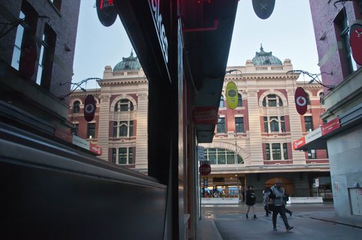 MELBOURNE, AUSTRALIA - JULY 29, 2018: Flinders street train station scene looks from Degrave laneway in Melbourne city center. There are tourists walks on the laneway in the morning.