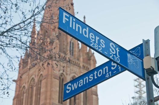 MELBOURNE, AUSTRALIA - JULY 29, 2018: Street signs of Flinders St and Swanston St in front of St Paul's Cathedral in Melbourne central business district near Federation square. The photo is taken in the afternoon.