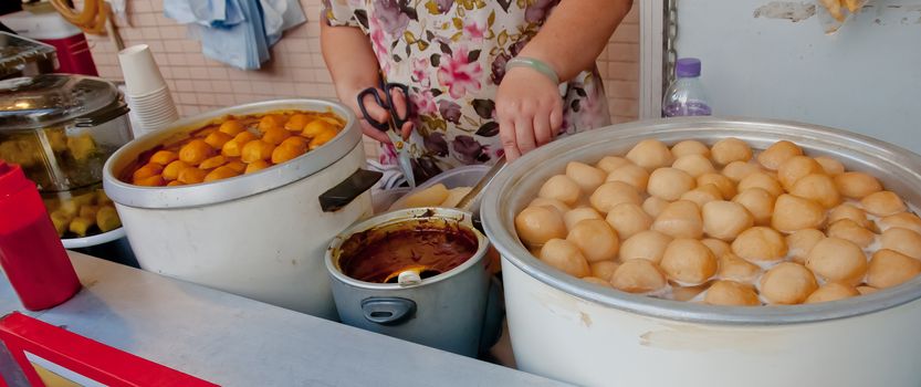 Hong Kong spicy marinated XO sauce fish balls boil in large soup pot serving hot at street food stall