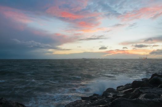 Dramatic splashing ocean wave in the evening with twilight sky in Winter at breakwater at St Kilda pier in Melbourne Australia