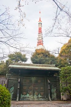 TOKYO, JAPAN - DECEMBER 1, 2018: Dark green metallic gate of a park of Zojo-ji Buddhist famous temple built from 1622. There is nobody in the photo.  There is Tokyo tower at the back of the temple.