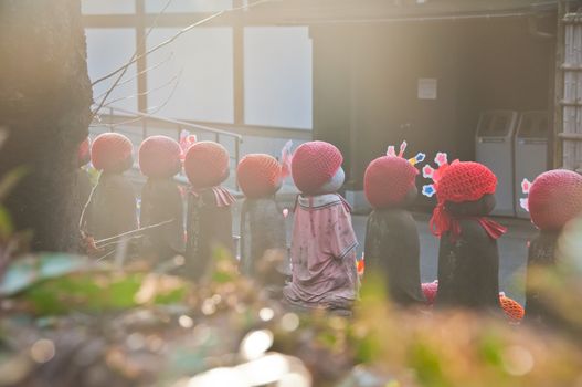 TOKYO, JAPAN - DECEMBER 1, 2018: Scene of children stone sculptures in the back park of  Zojo-ji Buddhist famous temple built from 1622. There is nobody in the photo.   The sculptures are covered with red beanies.