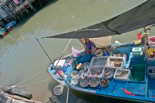 HONG KONG, HONG KONG SAR - NOVEMBER 18, 2018: Hong Kong Tai O local fisherman village in the Sunny afternoon. Female fisher is in her boat to sale fresh seafood.