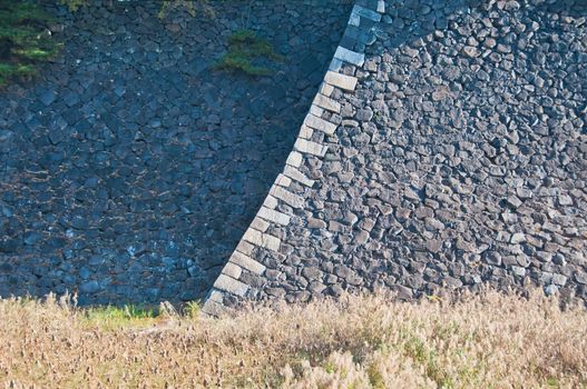 Large great strong rock stone fortress wall in sunny day abstract pattern background wallpaper