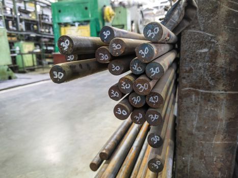 round 30 milimeter bars of steel in a metalworking shop - close-up with selective focus and blur