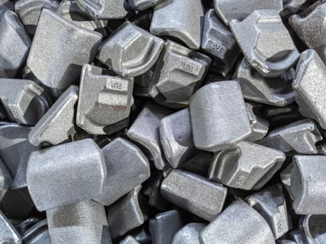 heap of gray steel forgings after shot blasting - close-up natural heavy industrial pattern with selective focus and grim mood