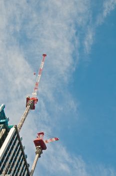 Underconstruction building in progress with many construction cranes and bright sunny blue sky with cloud