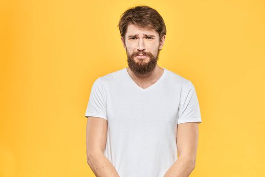 Bearded man emotions gestures with hands facial expression white t-shirt yellow background. High quality photo