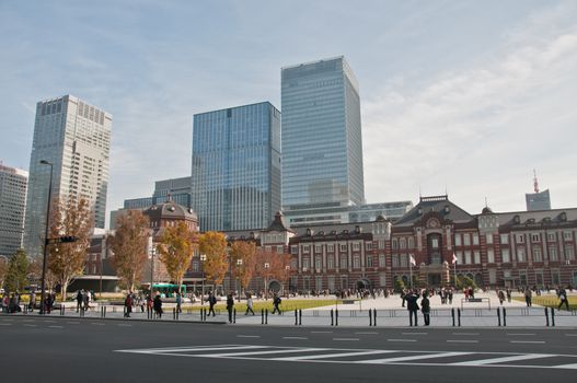 TOKYO, JAPAN - DECEMBER 1, 2018:  Tokyo Station railway building with Gingko yellow foliage leaves trees in late Autumn. There are many people walk on the street in front of the station.