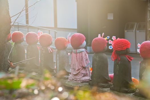 TOKYO, JAPAN - DECEMBER 1, 2018: Scene of children stone sculptures in the back park of  Zojo-ji Budhist famous temple built from 1622. There is nobody in the photo.   The sculptures are covered with red beanies.