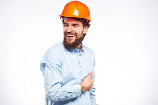 Cheerful man orange hard hat work industry professional lifestyle light background. High quality photo