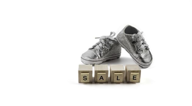 .Sale Concept - Children's sparkling little sneakers on wooden cubes with the word sale.