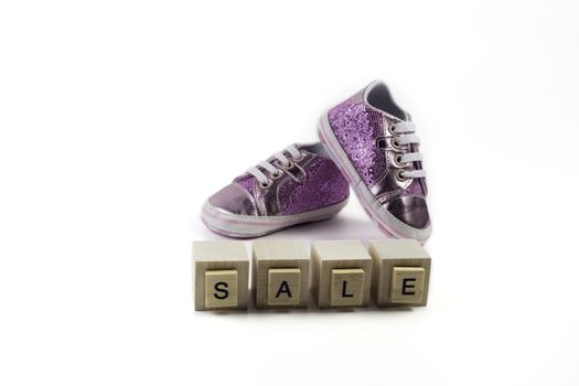 .Sale Concept - Children's sparkling little sneakers on wooden cubes with the word sale.