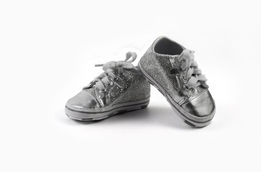 Children's sparkling little sneakers on white background.
