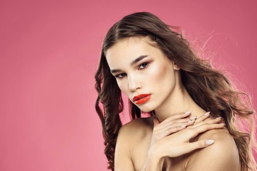 Beautiful woman with red lips on a pink background nude shoulders cropped view. High quality photo