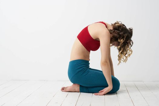 the girl is engaged in yoga on a light background Red T-shirt gesticulating with his hands. High quality photo