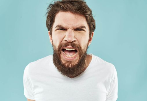 Aggressive man with a beard on a blue background cropped view. High quality photo