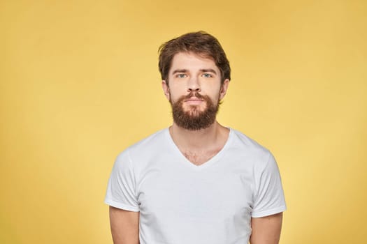 Bearded man on emotions white t-shirt fun lifestyle yellow background. High quality photo